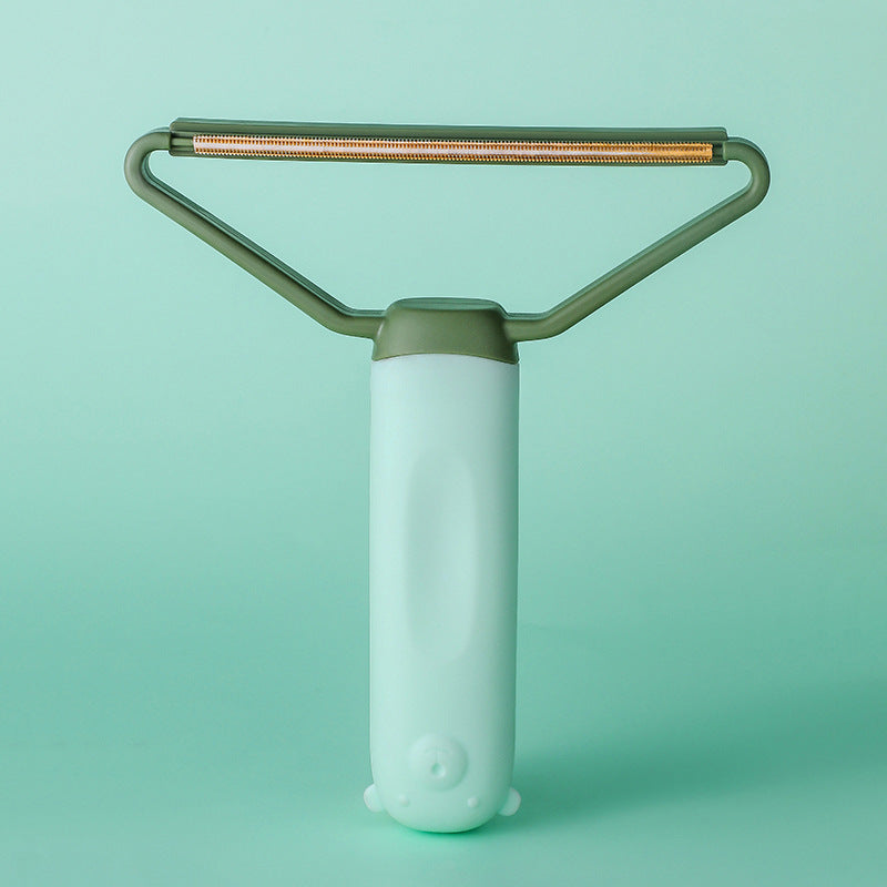 Green pet hair remover on matching green background showing wire scraper head — reusable cat and dog hair remover