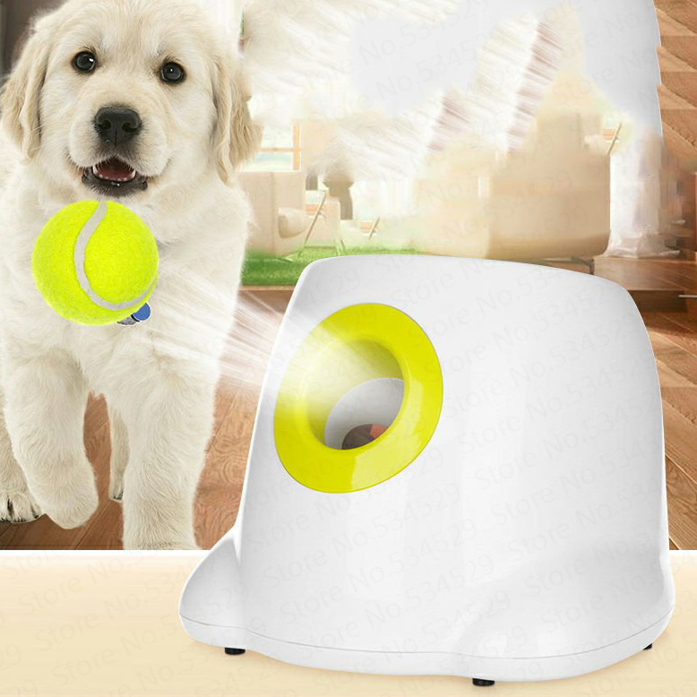 White device with a yellow ball on a wooden surface, with a dog and tennis ball in the background.