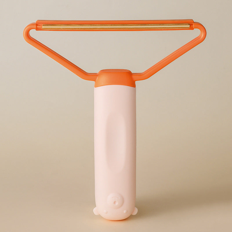 Orange and pink pet hair remover on beige background showing wire scraper head — reusable pet fur remover for sofas and carpets