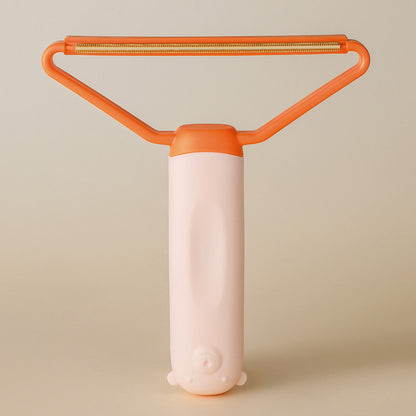 Orange and pink pet hair remover on beige background showing wire scraper head — reusable pet fur remover for sofas and carpets