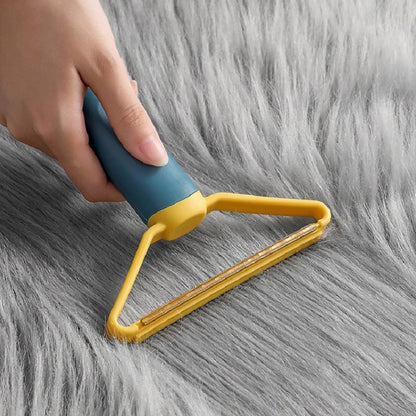 Hand using blue and yellow pet hair remover on long-pile grey fabric — reusable dog and cat hair remover for furniture