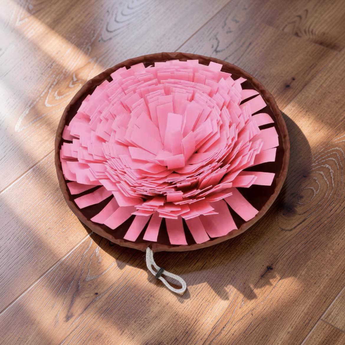 Pink felt snuffle mat on wooden floor in natural light — interactive slow feeder dog mat