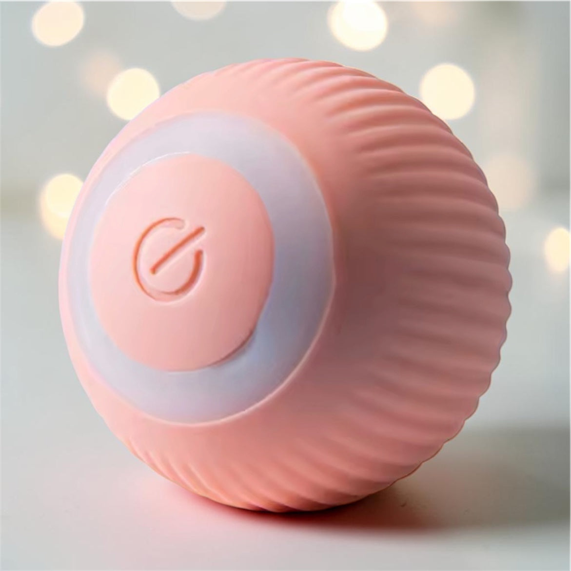 Pink ribbed automatic rolling ball toy with glowing ring on bokeh light background — interactive smart pet ball toy