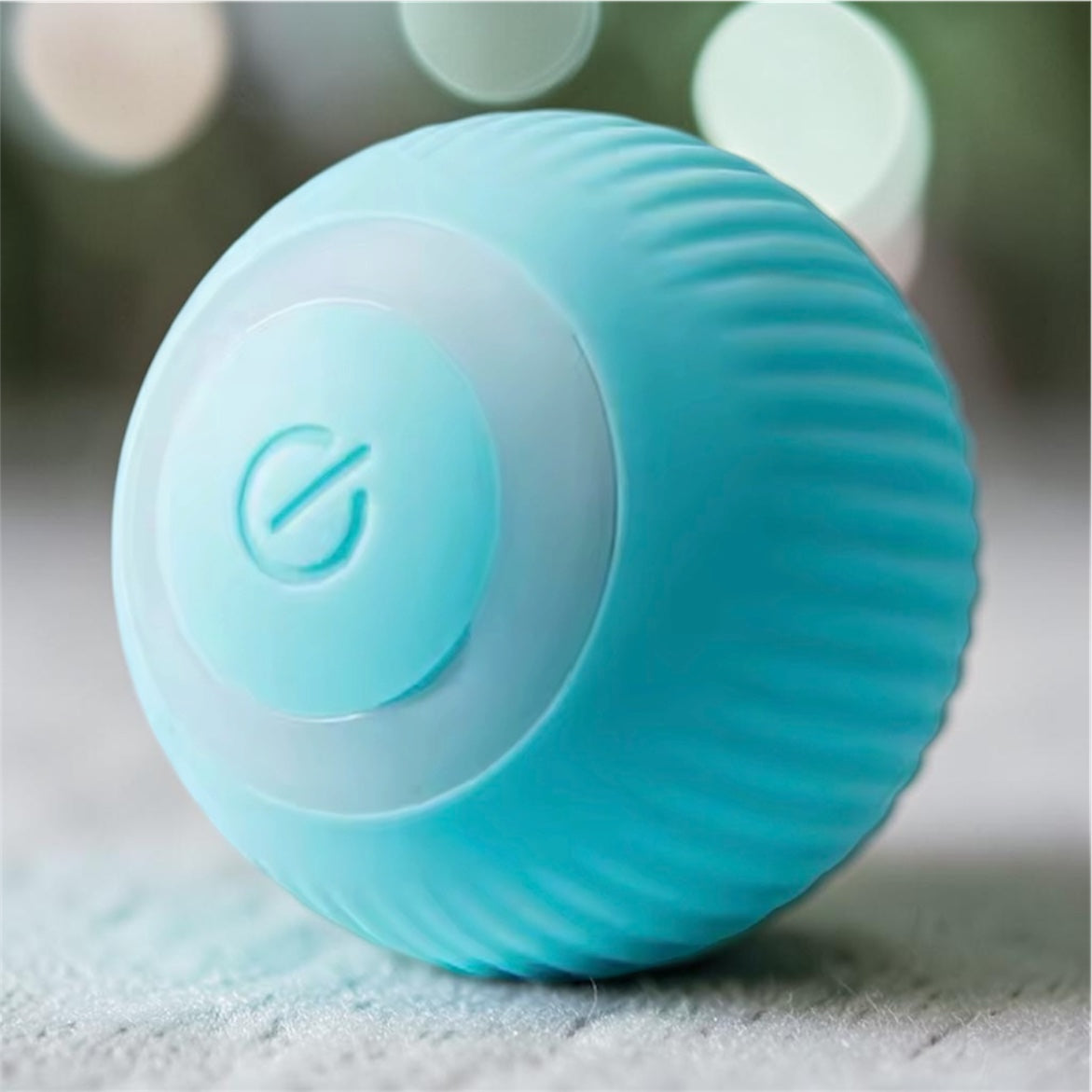 Blue ribbed automatic rolling ball toy with glowing ring on bokeh light background — interactive smart pet ball toy